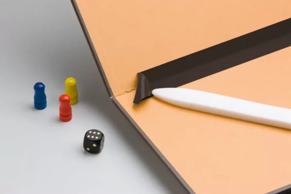 Pions, dé à jouer, carnet et stylo blanc